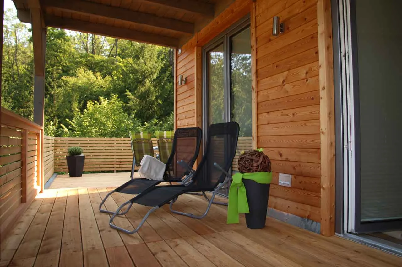 Zwei Liegestühle auf der geschützten Holzterrasse mit Blick in den Garten